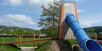 Foto: Der Spielplatz mitten im Dorf. Spielplatzgestaltung. Ein Förderturm mit Rutsche.