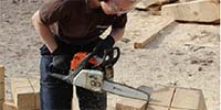 Foto: Eine Person bearbeitet mit einer Kettensäge ein Werkstück. Kettensägenseminar Ante/Südharz