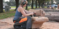 Foto: Eine Frau arbeitet mit einer Kettensäge an einem Objekt. Sägeseminar in Gudensberg.
