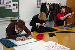 Foto: Studenten bei der Projektarbeit im Bereich der Konfektion stehen an einem Tisch und bearbeiten Stoffe.