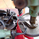 Foto: Ein Textil wird in einer Textilmaschine zwischen zwei Rädchen gezogen.