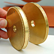 Foto: Zwei goldfarbene Metallscheiben mit einem mittigen Loch.