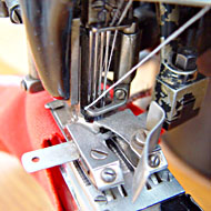 Foto: Nahaufnahme. Eine Textilmaschine bearbeitet ein Textil.