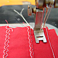 Foto: Nahaufnahme. Eine Textilmaschine vernäht ein Textil.