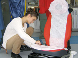 Foto: Eine Studierende arbeitet an einem Autositzbezug.