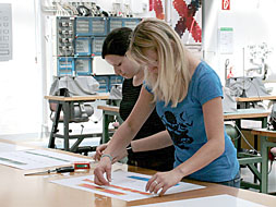 Foto: Zwei Studierende bekleben ein Plakat mit Mustern.
