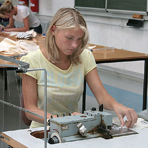 Foto: Eine Studierende führt an einer Maschine textile Stoffe zusammen.