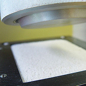 Foto: Faserstoffprüfung. Ein eingespannter Stoff wird mit einer Prüfmaschine getestet.