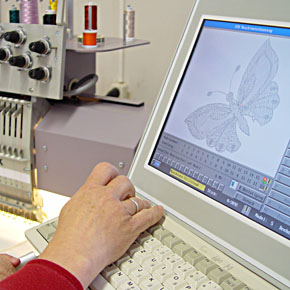 Foto: Ein Hand gibt Eingaben auf eine Tastatur. Auf einem Bildschirm ist die Grafik eines Schmetterlings zu sehen.