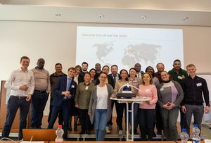 Gruppenfoto der Teilnehmer, hinter ihnen eine Weltkarte