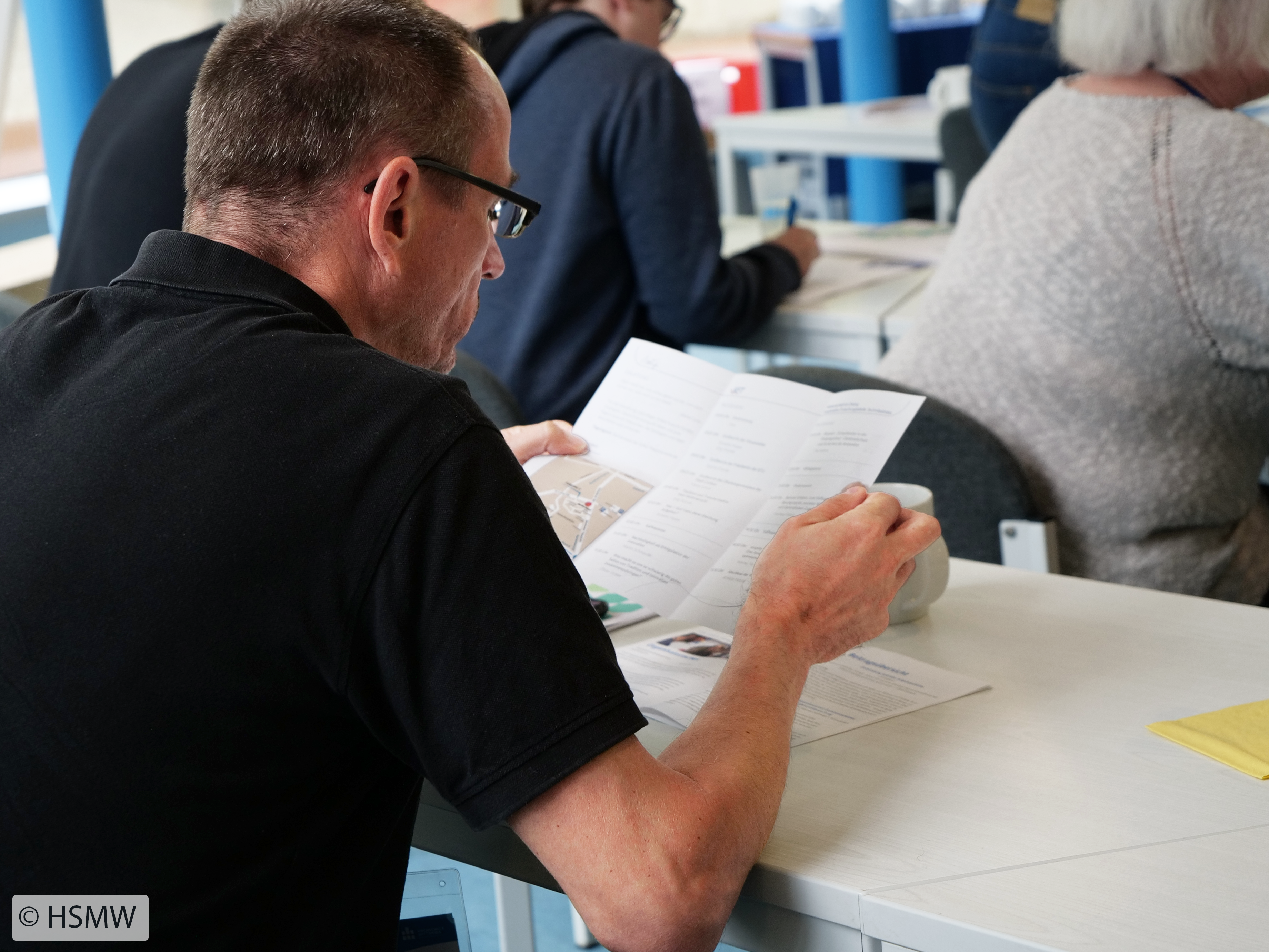 Foto: ein Mann betrachtet einen Flyer