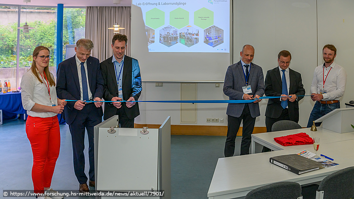 Foto: Eröffnung des "Living Lab Hybride Arbeitssysteme", Teilnehmer zerschneiden das Eröffnungsband