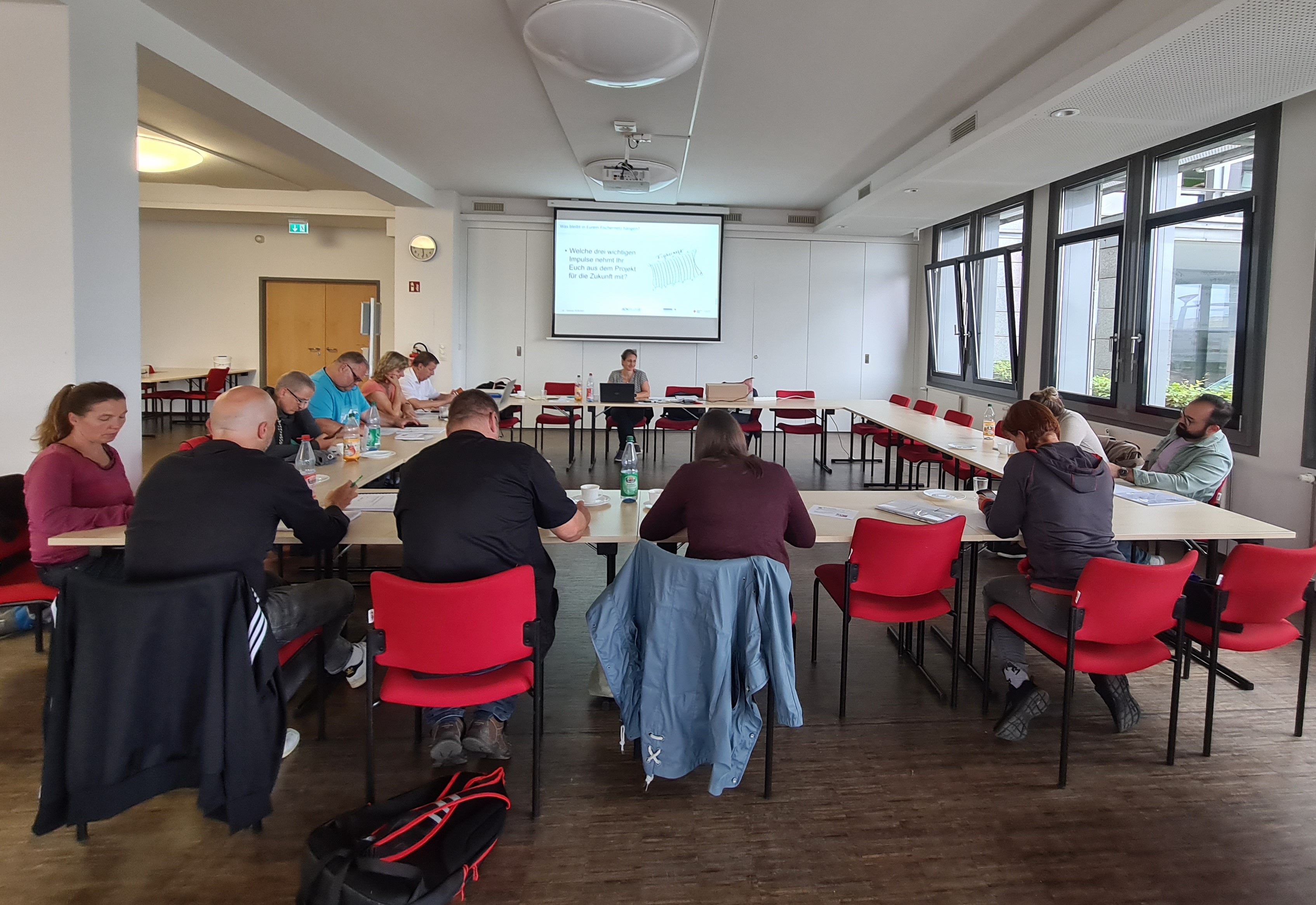 Foto: Abschlussworkshop der 3.Phase des TEK-Forschungsprojektes, DRK Landesverband Dresden, Teilnehmer sitzen in großer Runde und hören einem Vortrag zu 