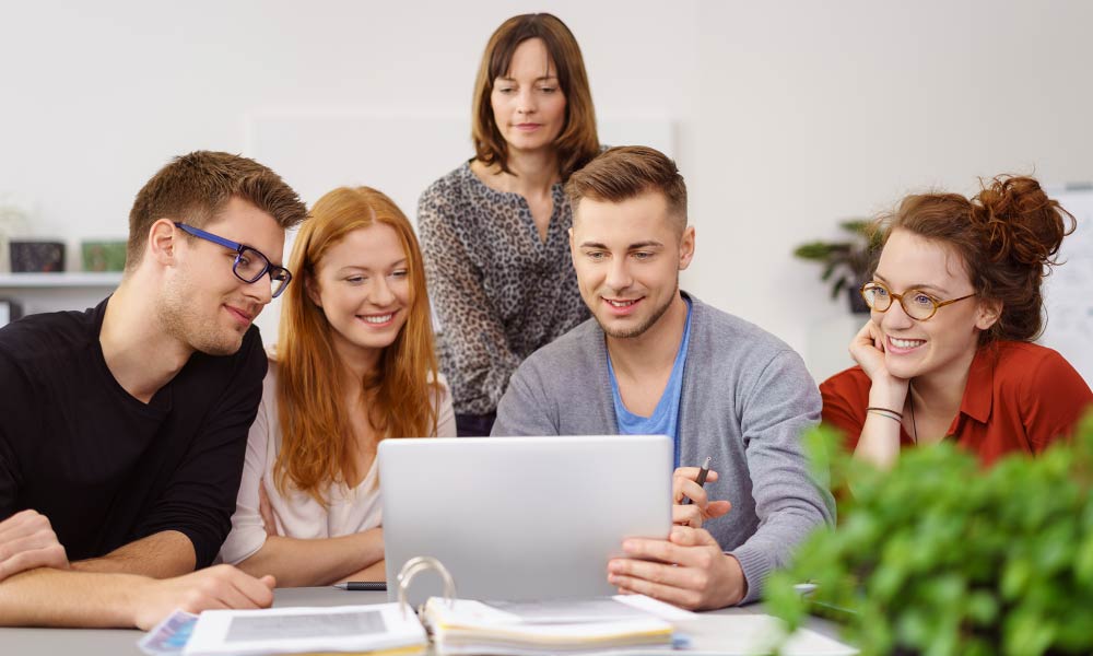 Foto: Eine Gruppe von Studierenden schauen in einen Notebook (Quelle: Adobestock_112961136: AdobeStock/contrastwerkstatt)