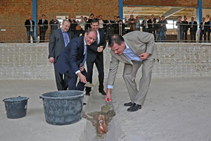 Michael Bartsch von der GIIZ, Sachsens Innenminister Markus Ulbig, Bert Hoffmann von der Firma Bauconzept und GIIZ-Chef Tobias Teich mauern eine Zeitkapsel in das ehemalige Schwimmbecken.