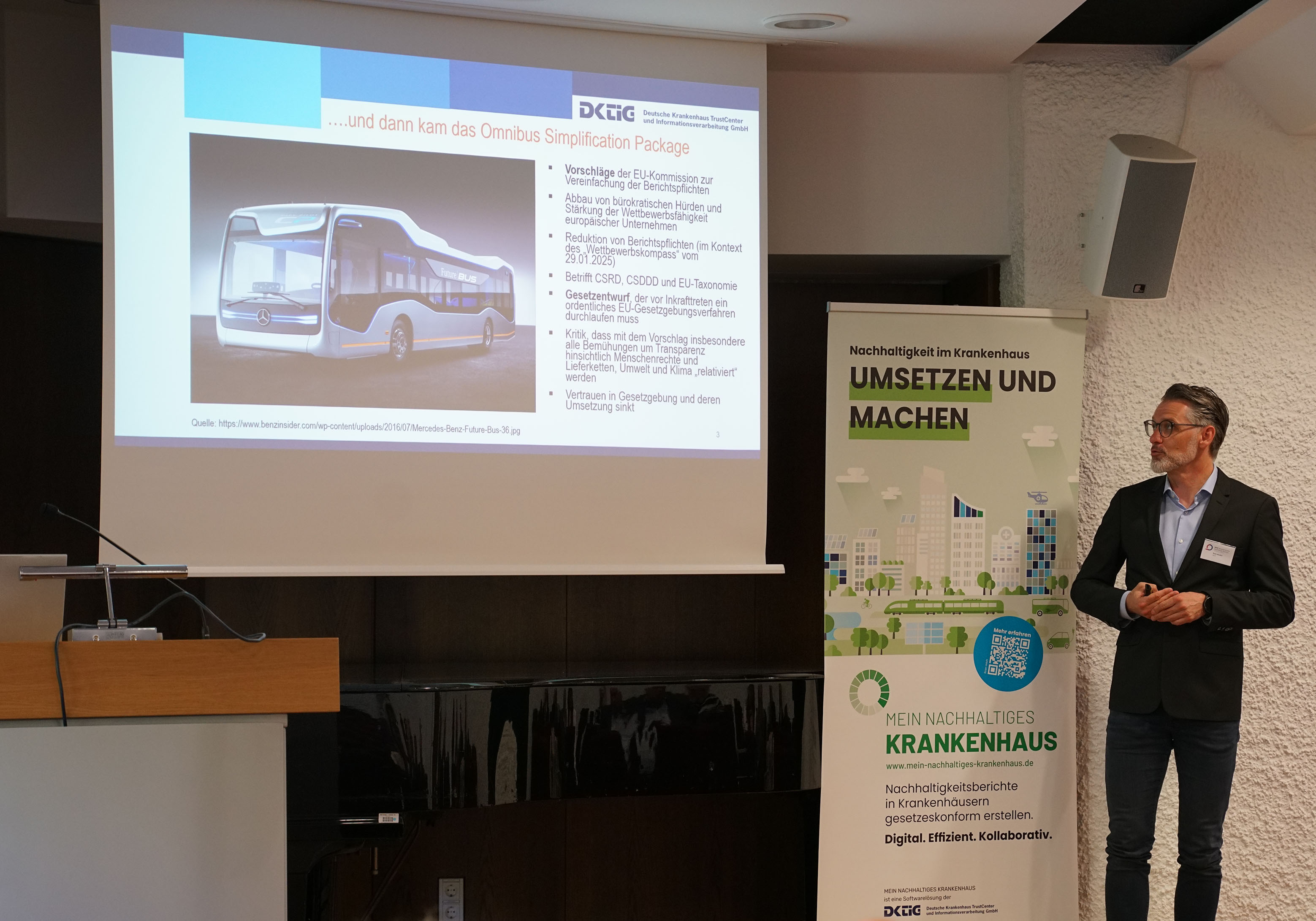 Mann im Anzug hält eine Präsentation vor Publikum