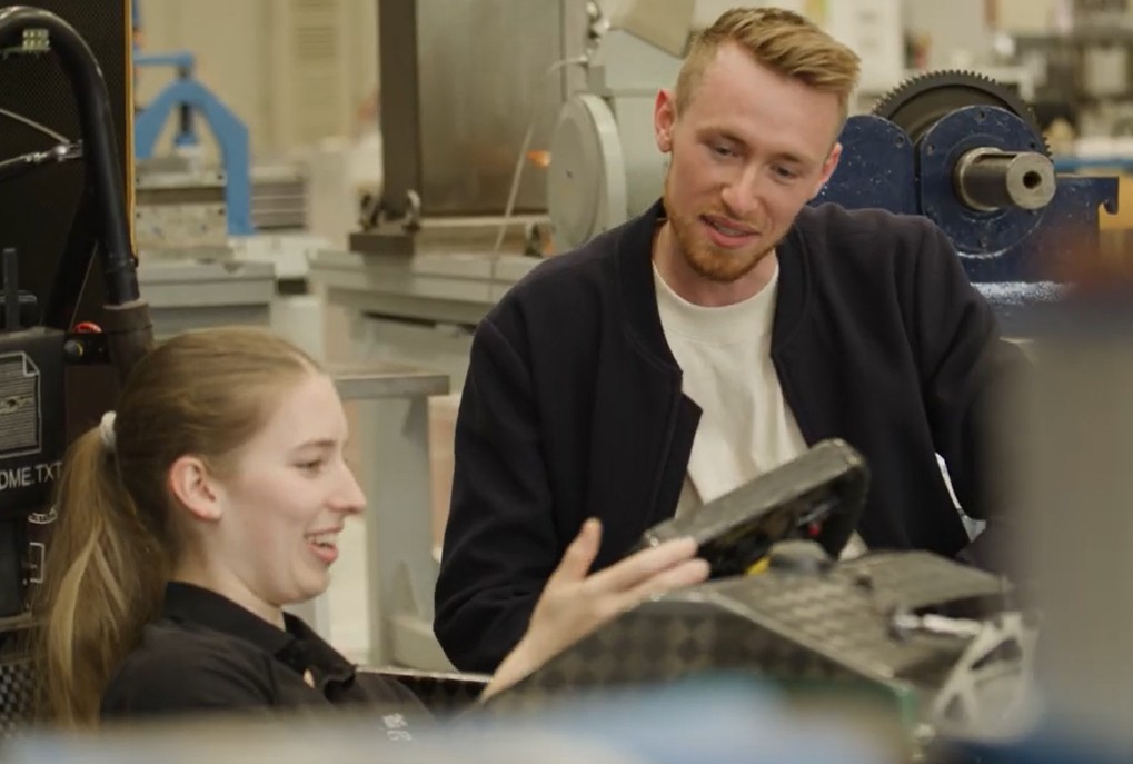 Zwei Studierende diskutieren in einer Laborumgebung. 