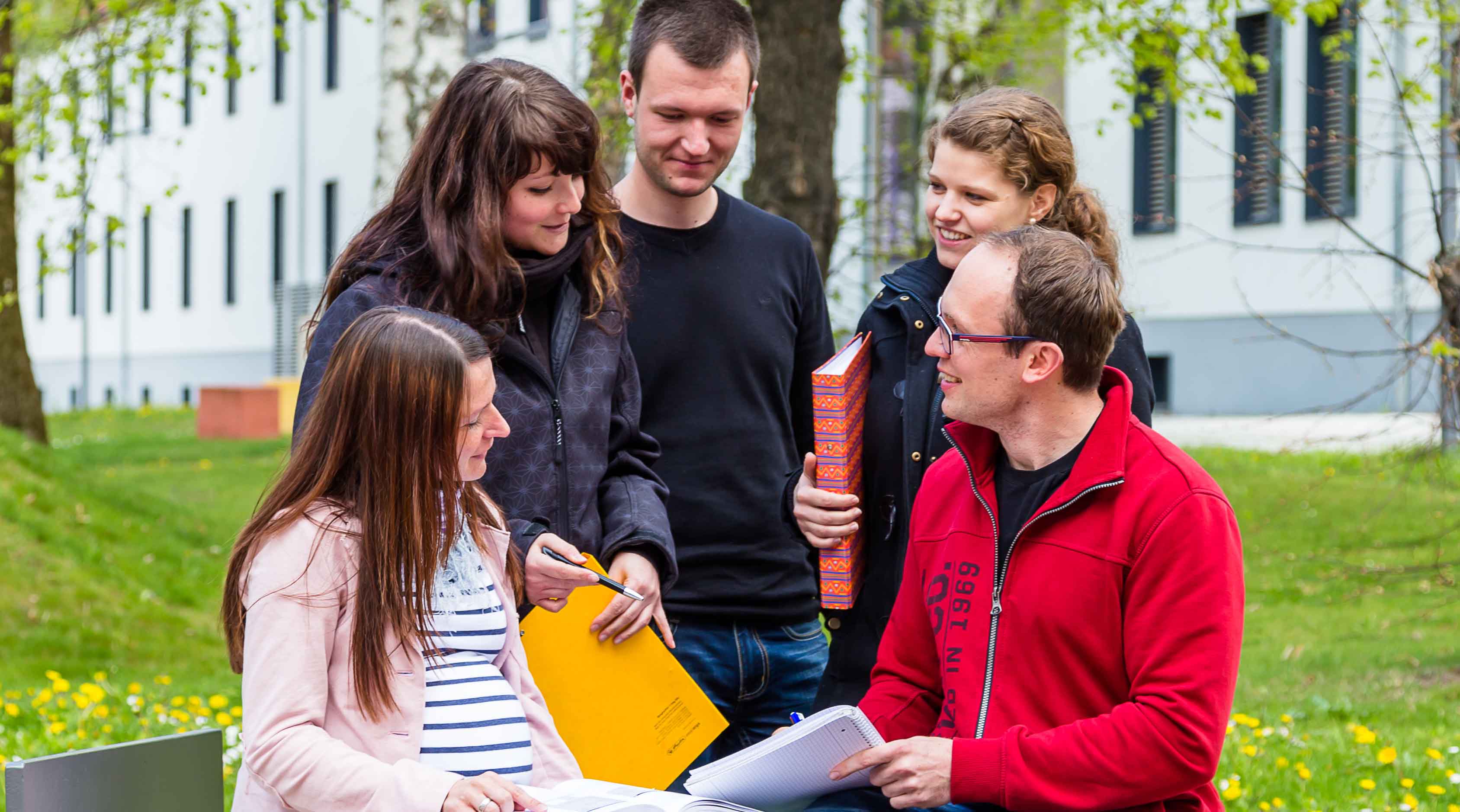 Foto: Fünf Studierende sitzend und stehend im Außenbereich des Campus Scheffelberg tauschen sich untereinander aus.