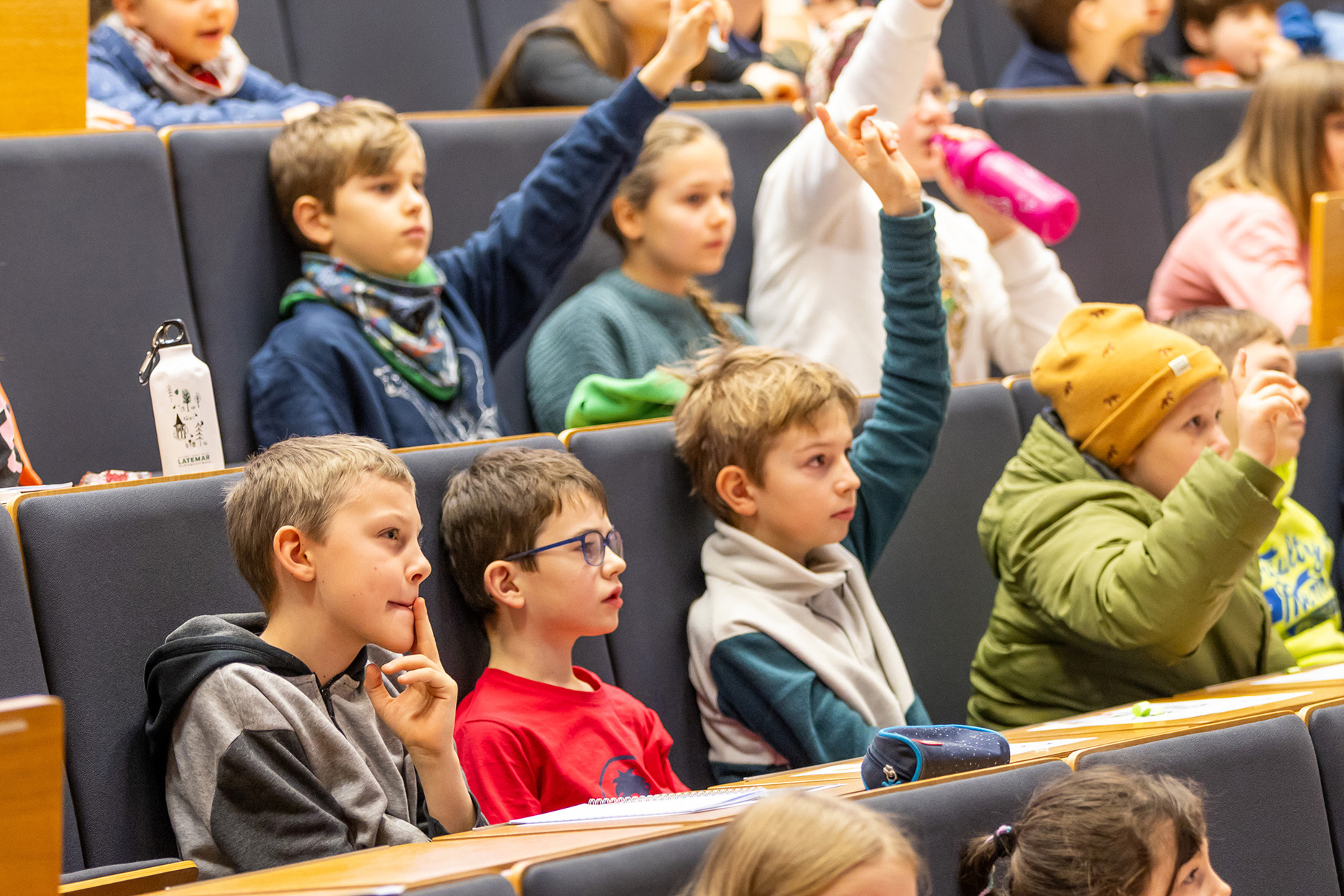 Kinder sitzen im Hörsaal und hören aufmerksam zu 
