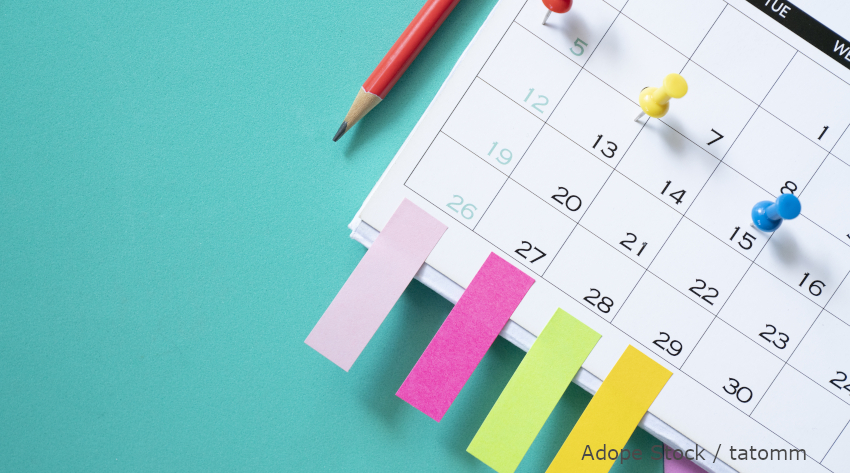 Foto: Ein Kalenderblatt mit Pinnadeln und farbigen Klebestreifen.